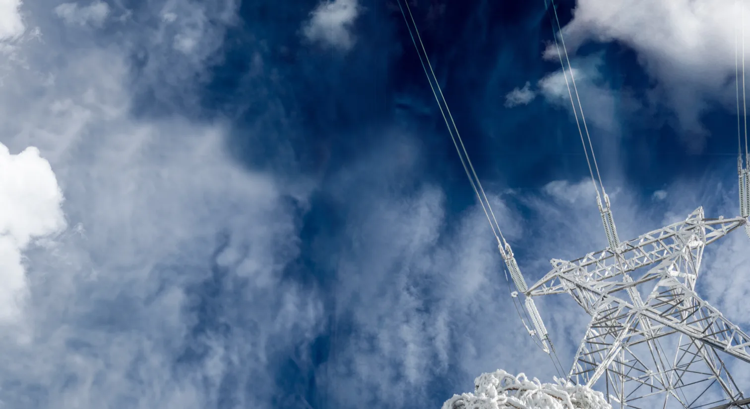 Strømmast sett nedenfra med blå himmel og skyer over